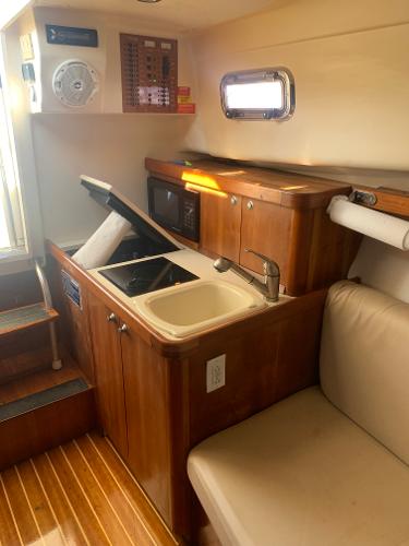 2004 Mainship Pilot 30-II Sedan interior with kitchenette, sink, and seating area.