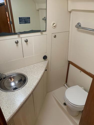 2004 Mainship Pilot 30-II Sedan bathroom with sink, toilet, and storage cabinets.