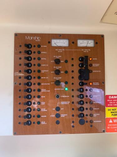 Control panel of a 2004 Mainship Pilot 30-II Sedan boat with various switches and gauges.