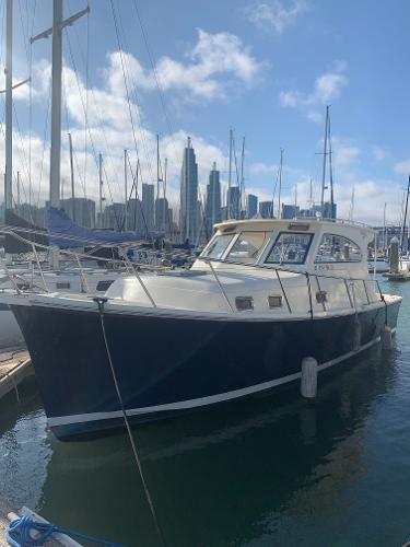 2004 Mainship Pilot 30-II Sedan docked in marina with city skyline background.