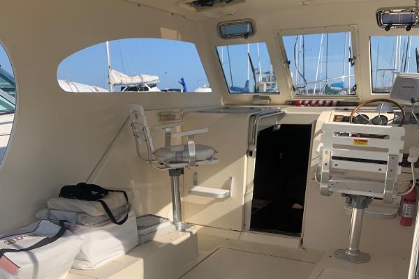 2004 Mainship Pilot 30-II Sedan interior with helm, seating, and nautical equipment.