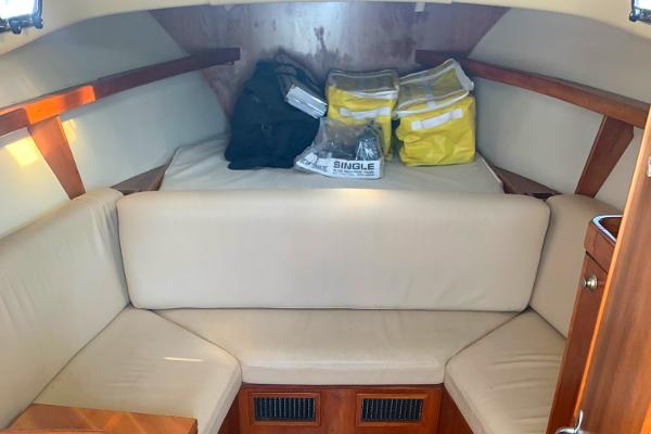 2004 Mainship Pilot 30-II Sedan cabin interior with beige seating and storage bags.