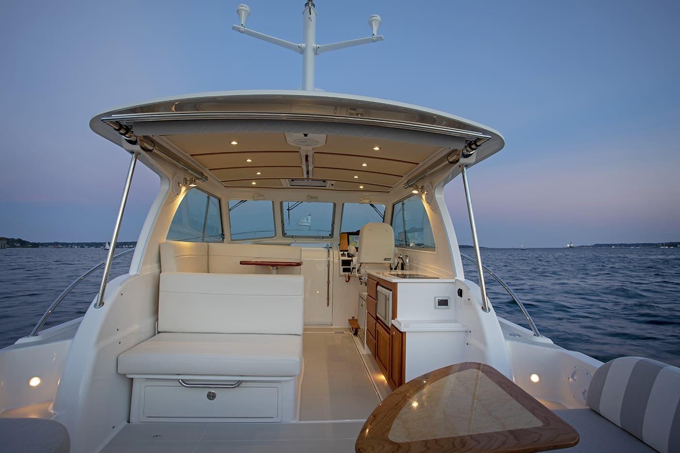 2026 Back Cove 34O yacht interior with seating and ocean view at sunset.