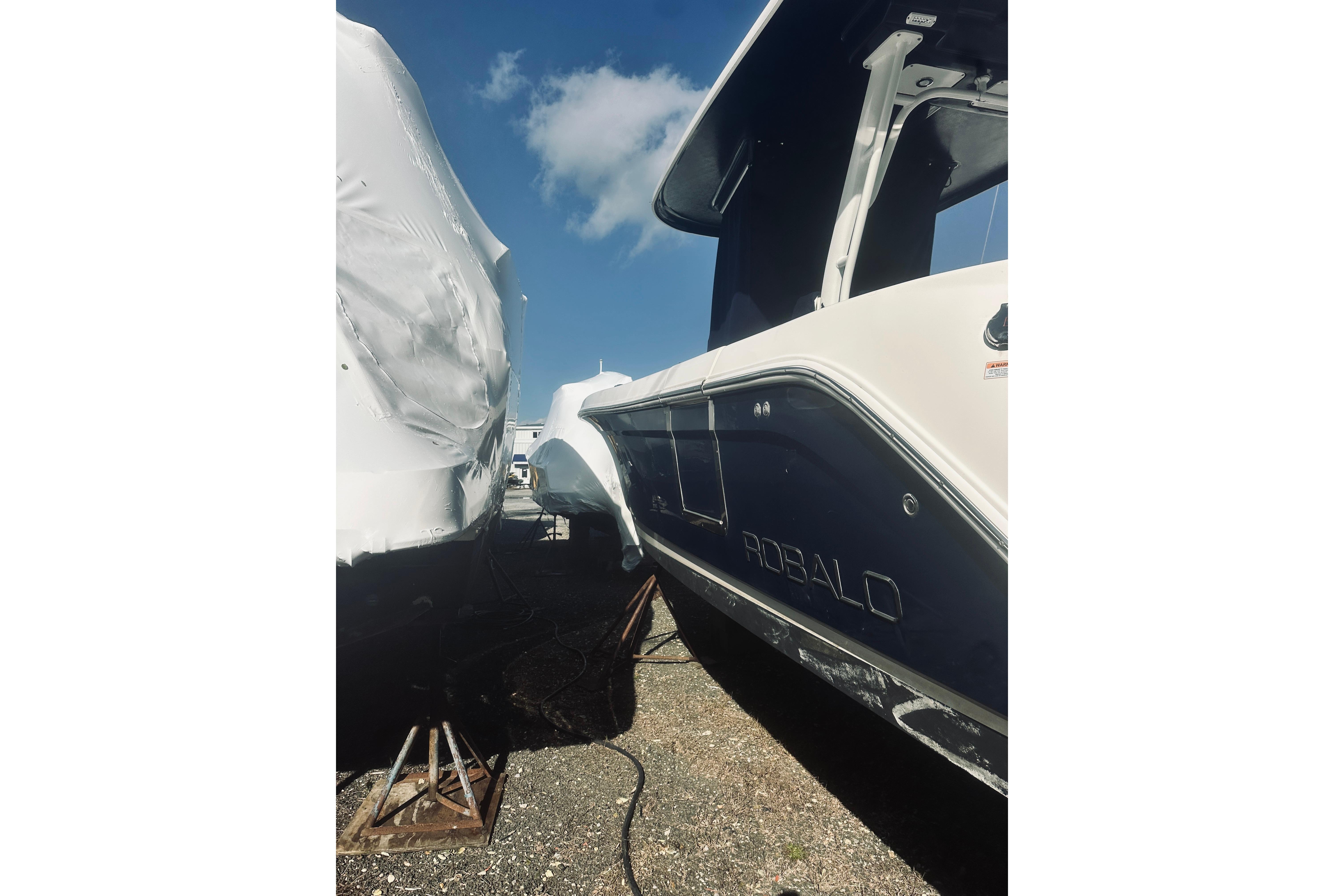 2022 Robalo R272 Center Console boat in storage, side view under blue sky.