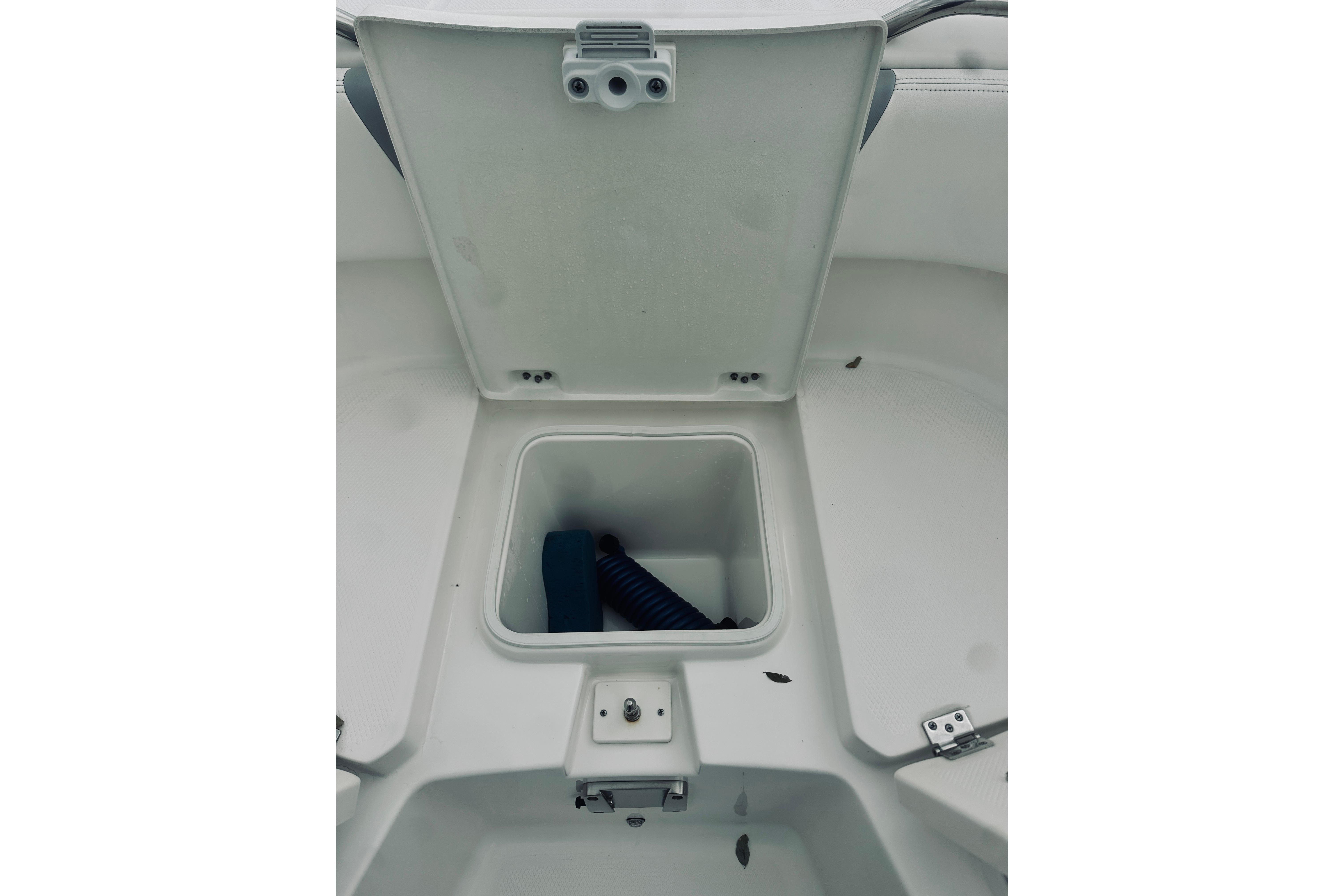 2022 Robalo R272 Center Console storage compartment with open lid and coiled rope inside.