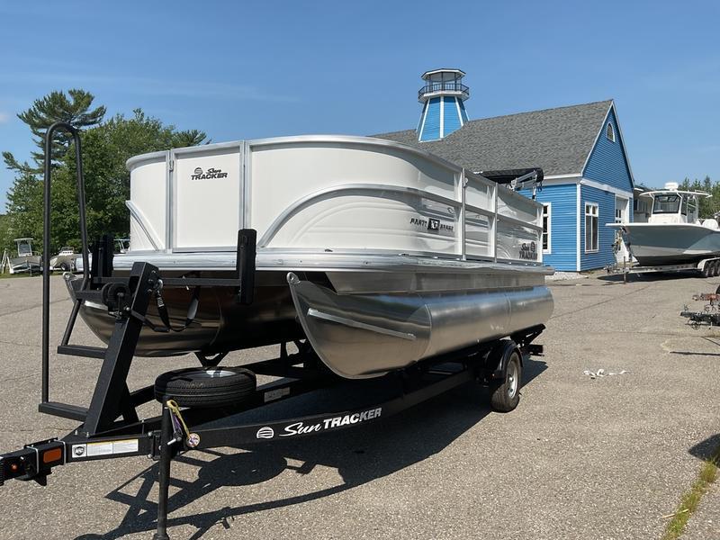 2026 Sun Tracker PB 16 DLX pontoon boat on trailer, parked near blue building.