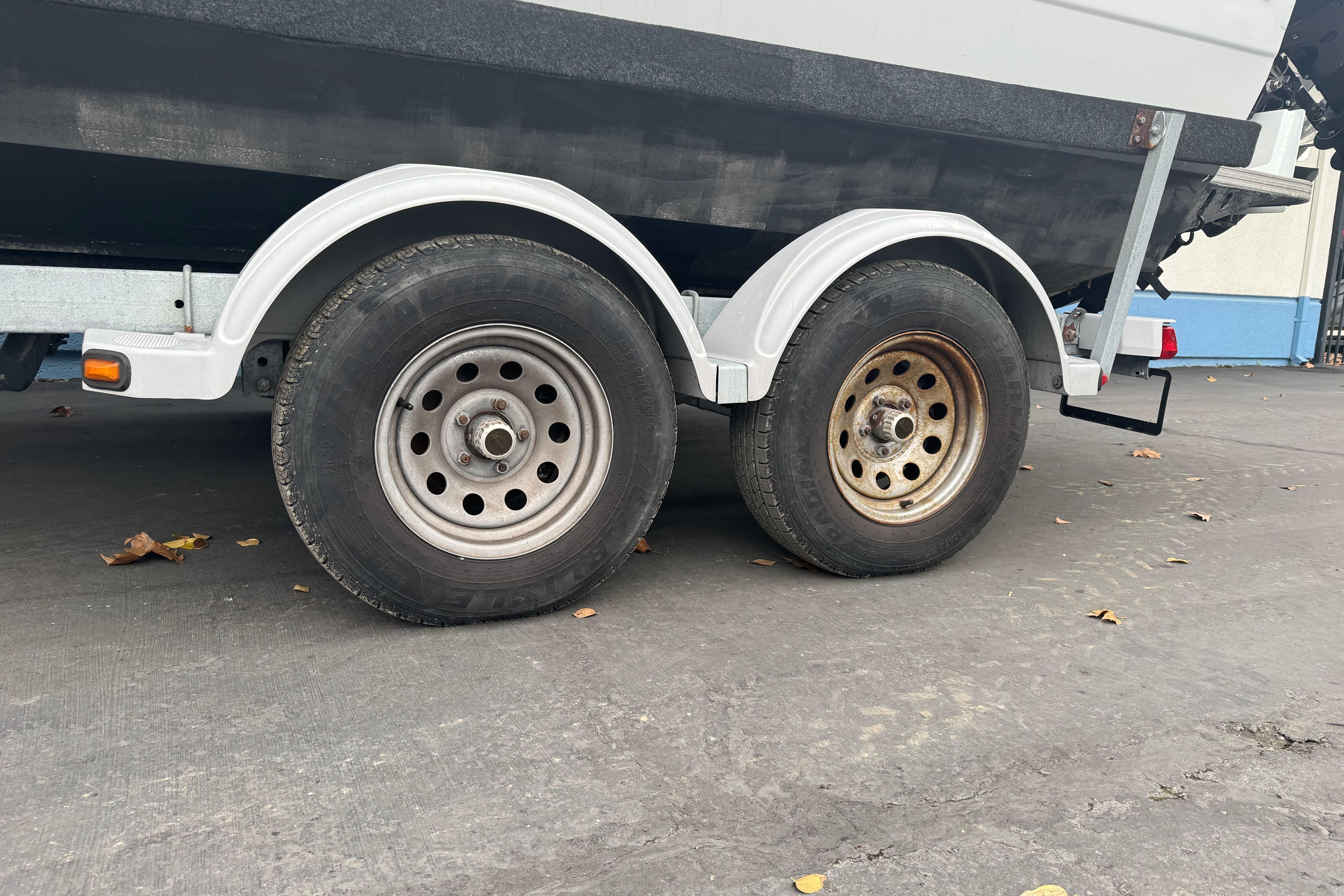 Trailer wheels of a 2021 KingFisher 2025 Escape HHT boat on pavement.
