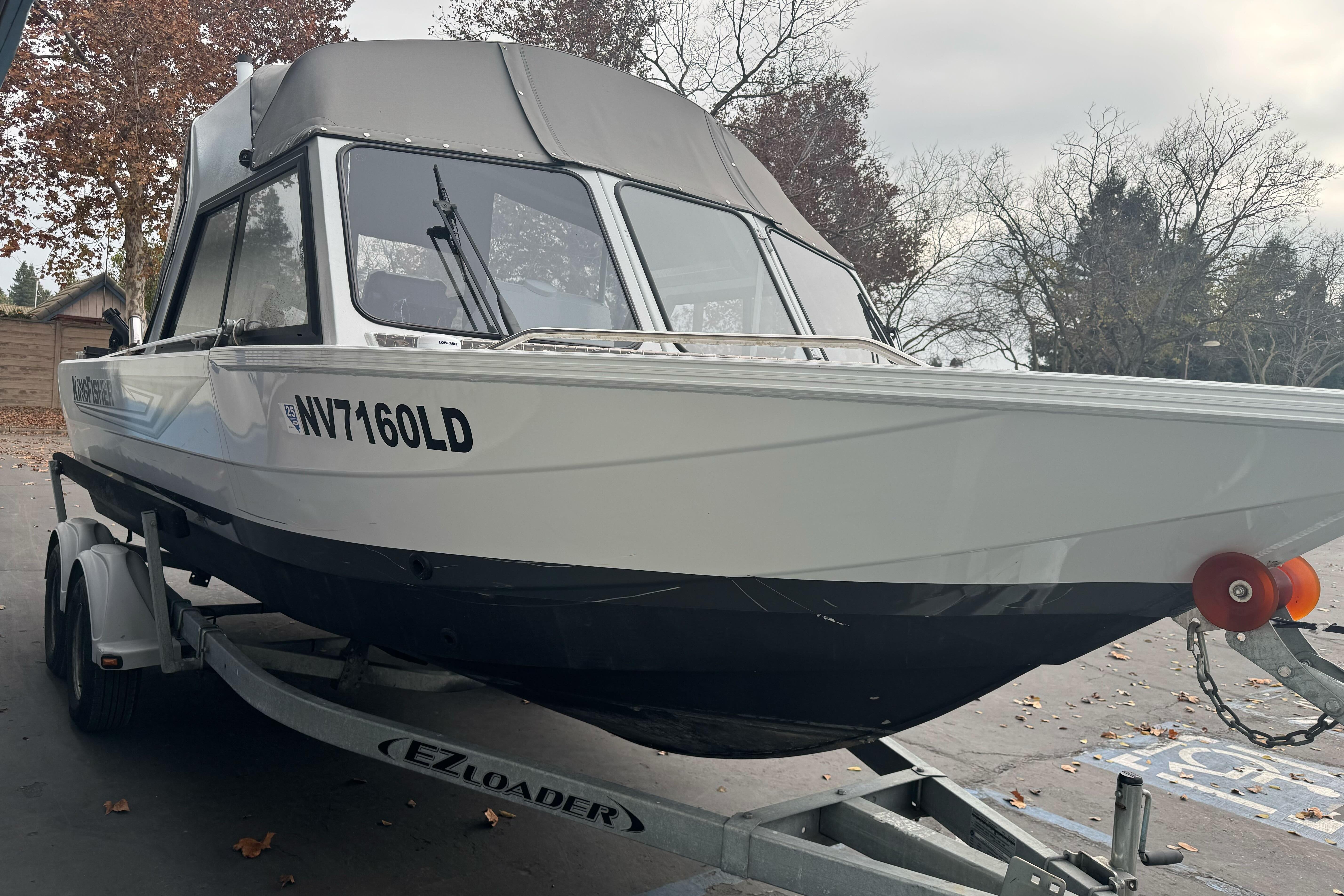 KingFisher 2025 Escape HHT boat on trailer, parked outdoors, autumn setting.