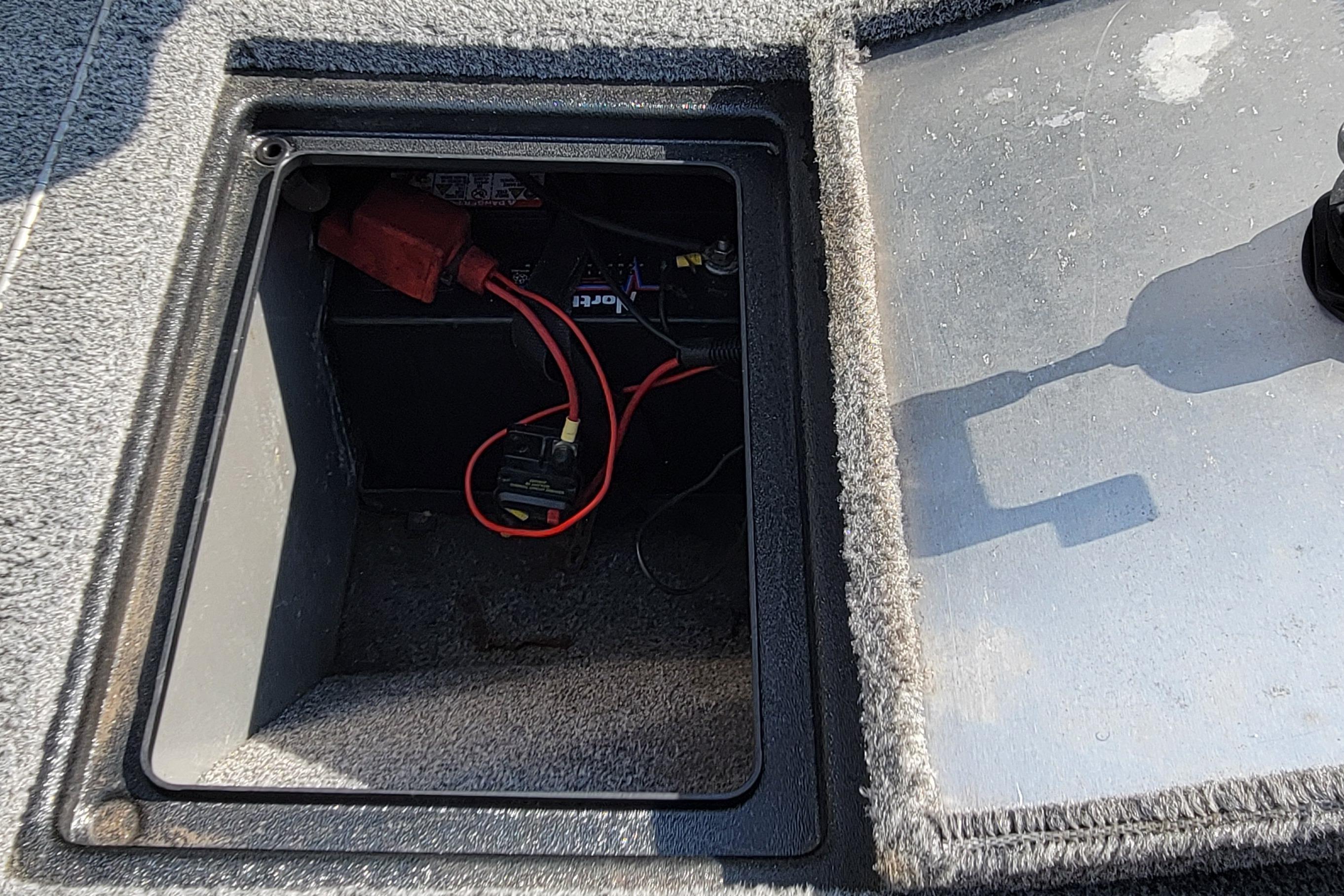 Battery compartment of a 2016 Tracker boat with visible wiring and connections.