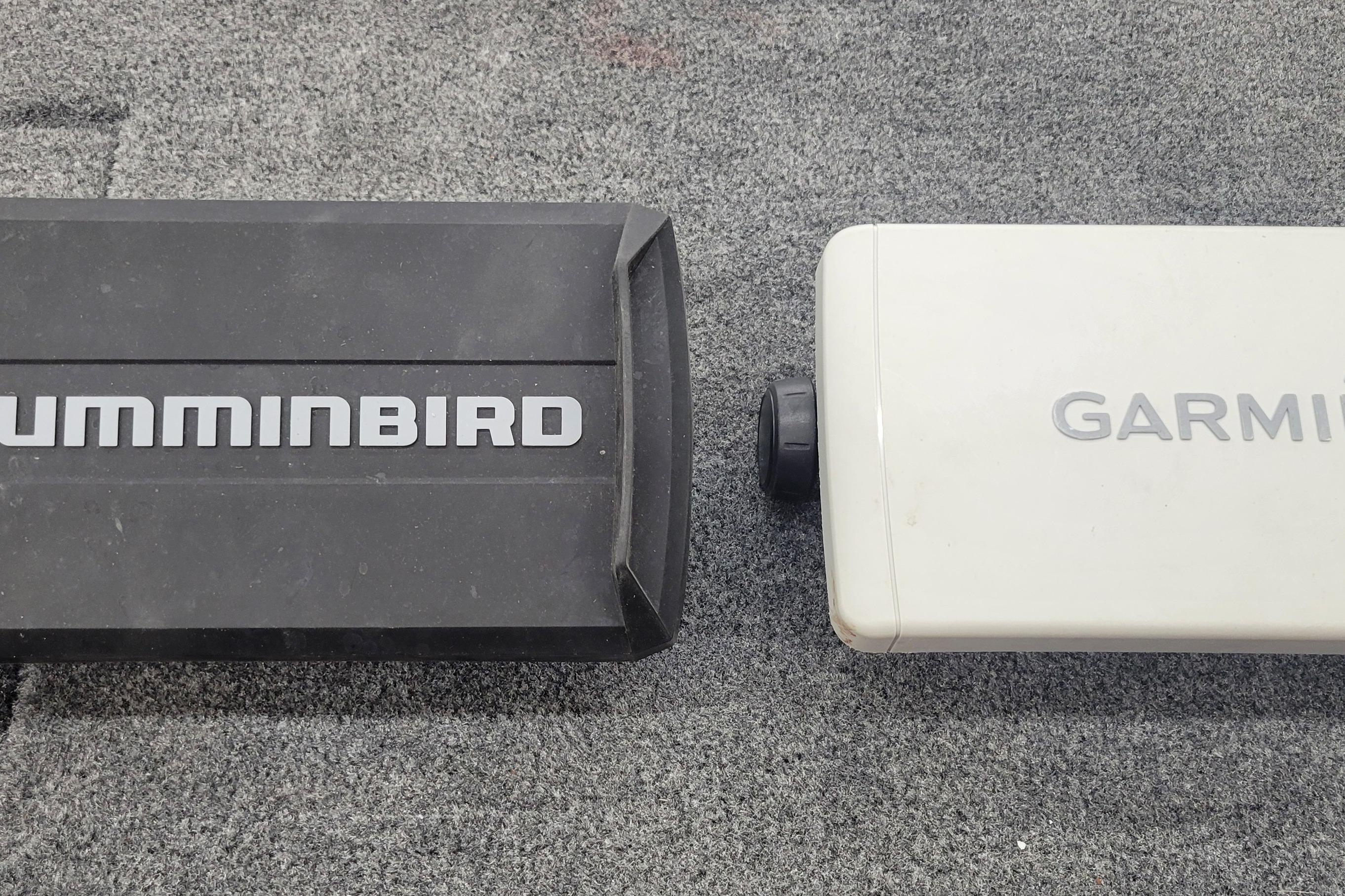 Two electronic devices, Humminbird and Garmin, on a gray carpeted surface.
