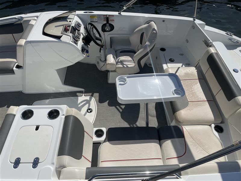 Modern 2021 Tahoe 1950 boat interior with seating, steering, and table on water.