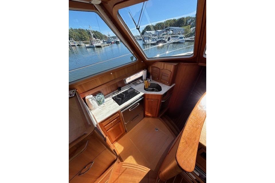 2012 Sabre 42 Salon Express interior with kitchenette, featuring wood cabinetry and marina view.