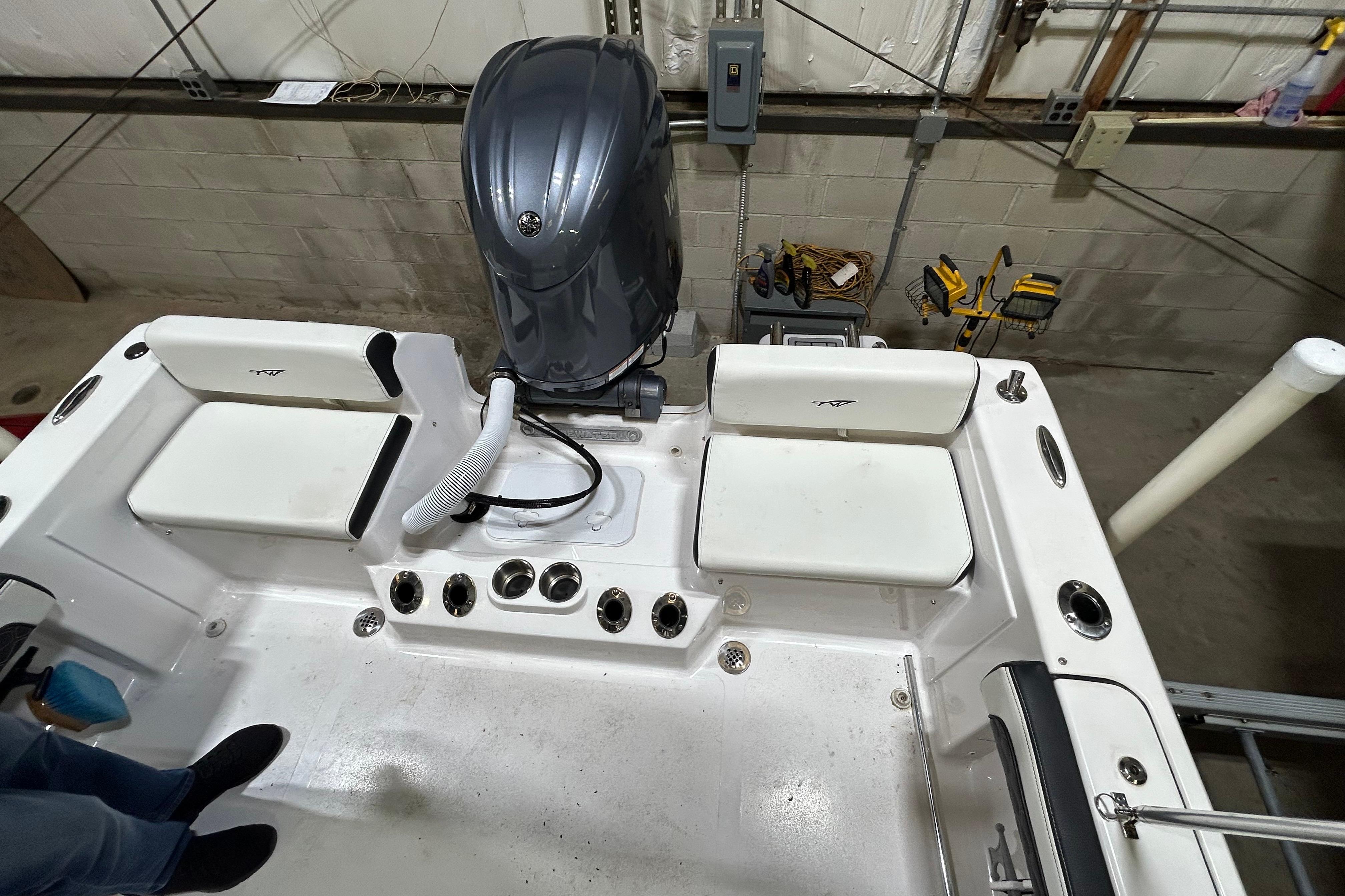 2024 Tidewater 198 CC Adventure boat interior with engine and seating in a garage setting.