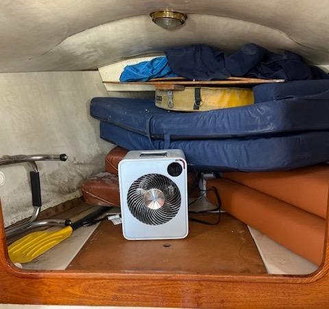 Interior cabin of a 1979 Lancer Sloop with cushions and a portable fan.