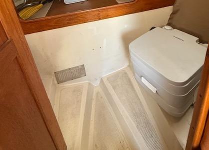 1979 Lancer Sloop interior with compact portable toilet and wooden accents.