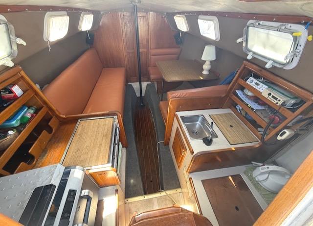 Interior of a 1979 Lancer Sloop sailboat with cozy seating, kitchenette, and wooden accents.