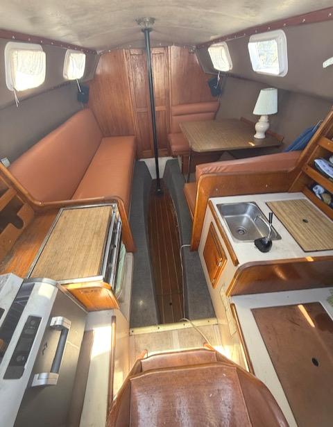 Interior of a 1979 Lancer Sloop sailboat with cozy seating and compact kitchen area.