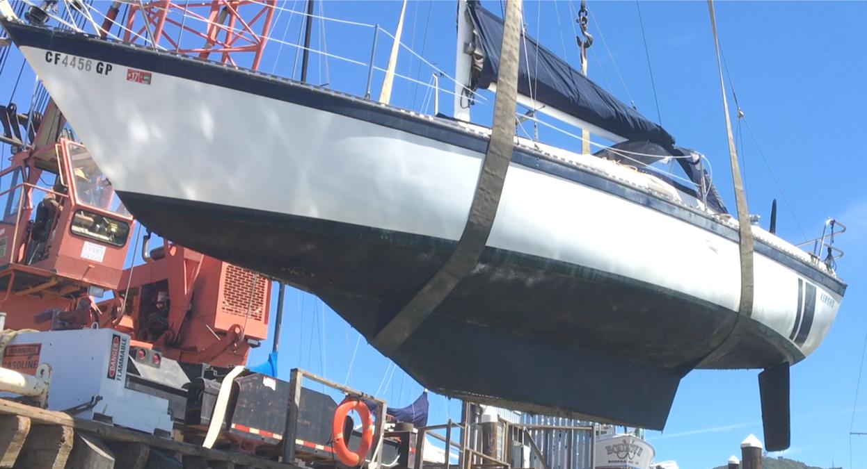 1979 Lancer Sloop sailboat being lifted by crane at a dock.