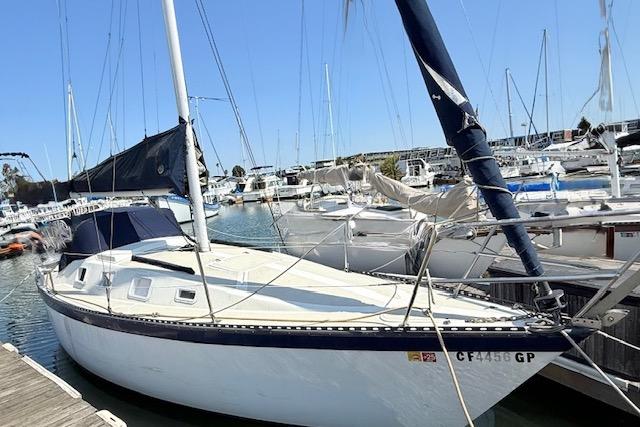 1979 Lancer Sloop sailboat docked in a marina under clear blue skies.