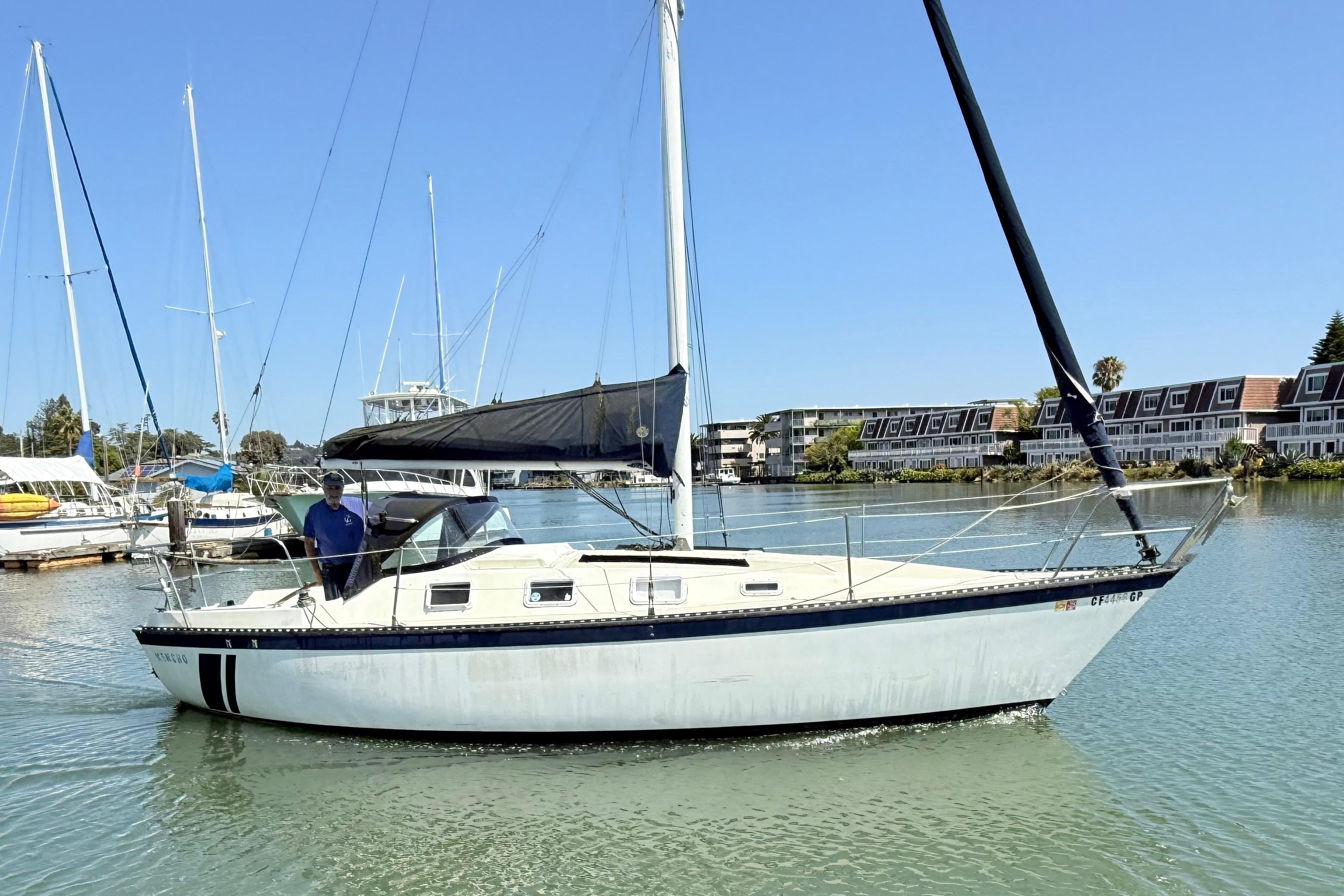 1979 Lancer Sloop sailboat docked in a marina under clear blue skies.