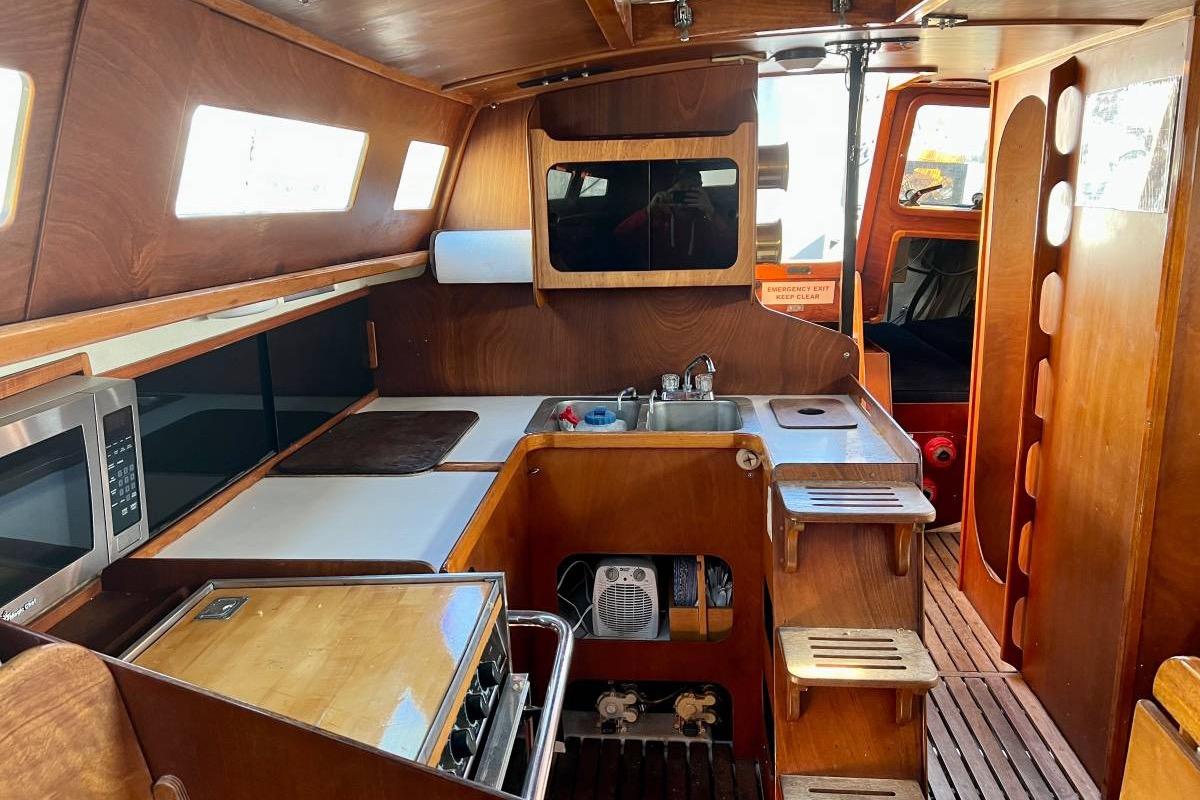 Interior of 1982 Santa Cruz 50 sailboat with wooden cabinetry and kitchen amenities.