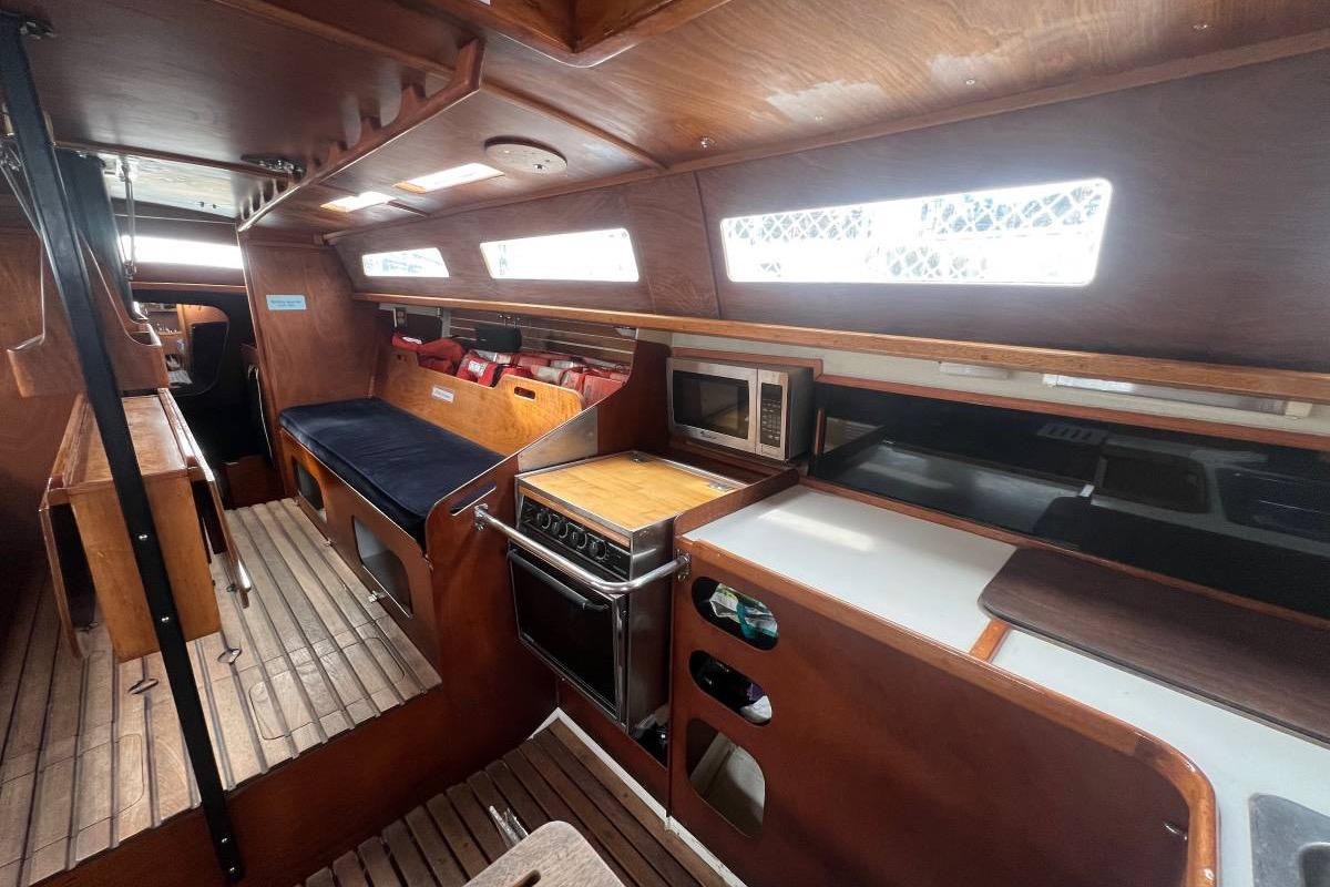 Interior of a 1982 Santa Cruz 50 sailboat with wooden finishes and kitchen amenities.