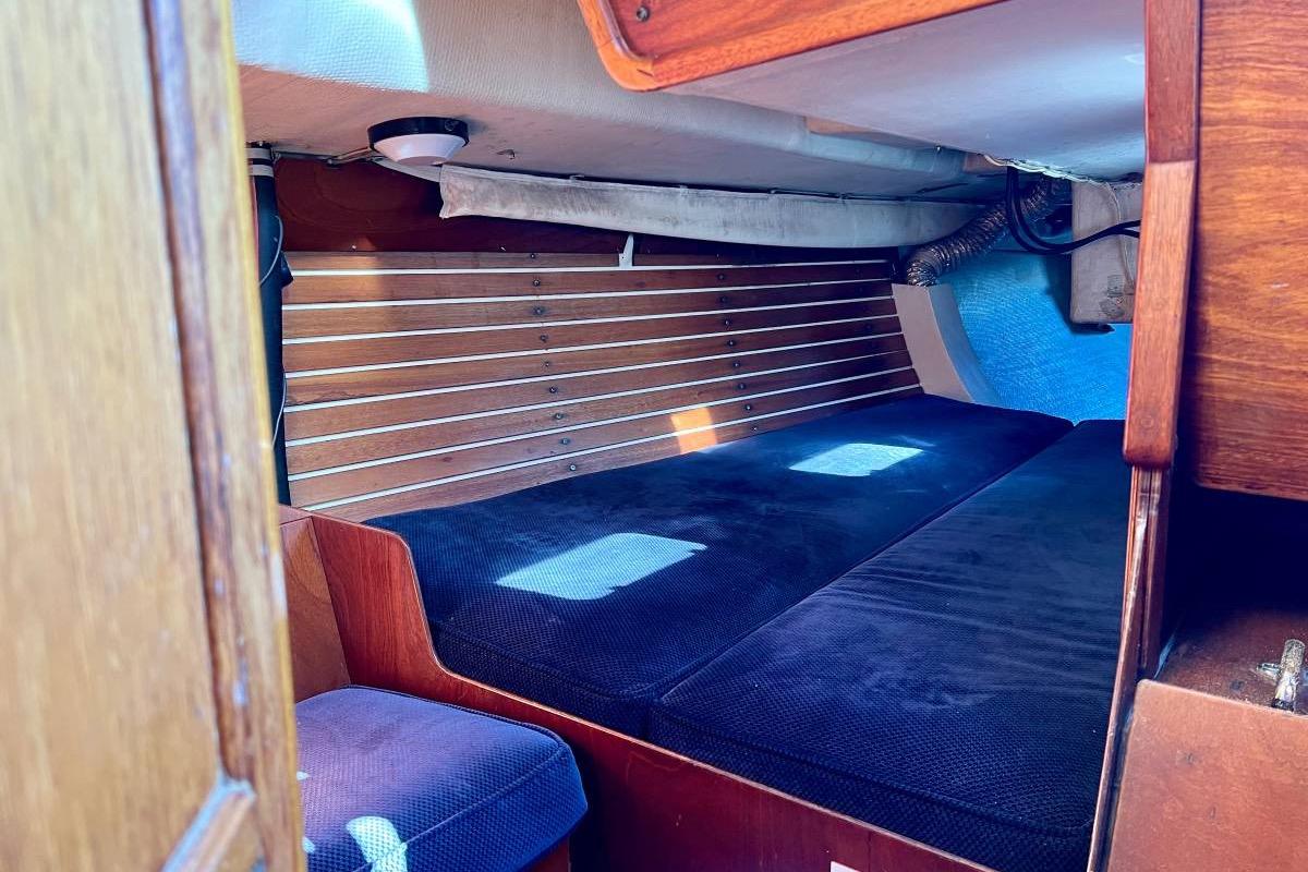 Interior cabin of a 1982 Santa Cruz 50 sailboat with wooden paneling and blue cushions.