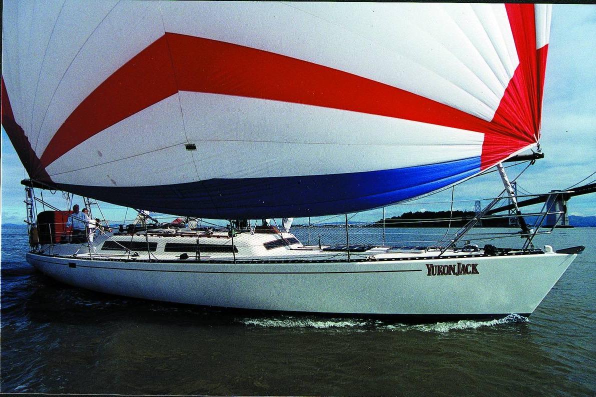 1982 Santa Cruz 50 sailboat "Yukon Jack" with colorful spinnaker on open water.