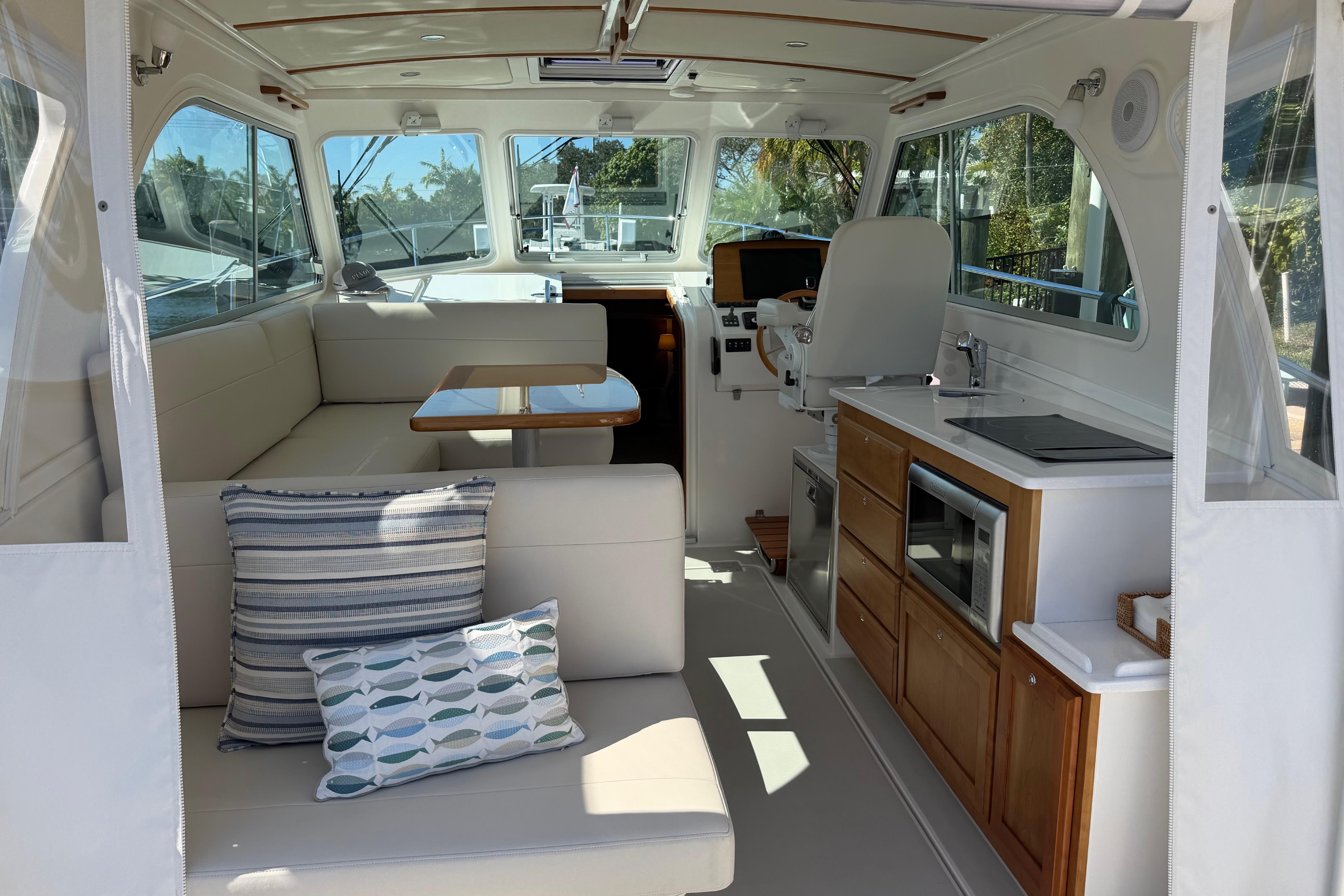2023 Back Cove 340 interior with seating, table, kitchenette, and helm station.