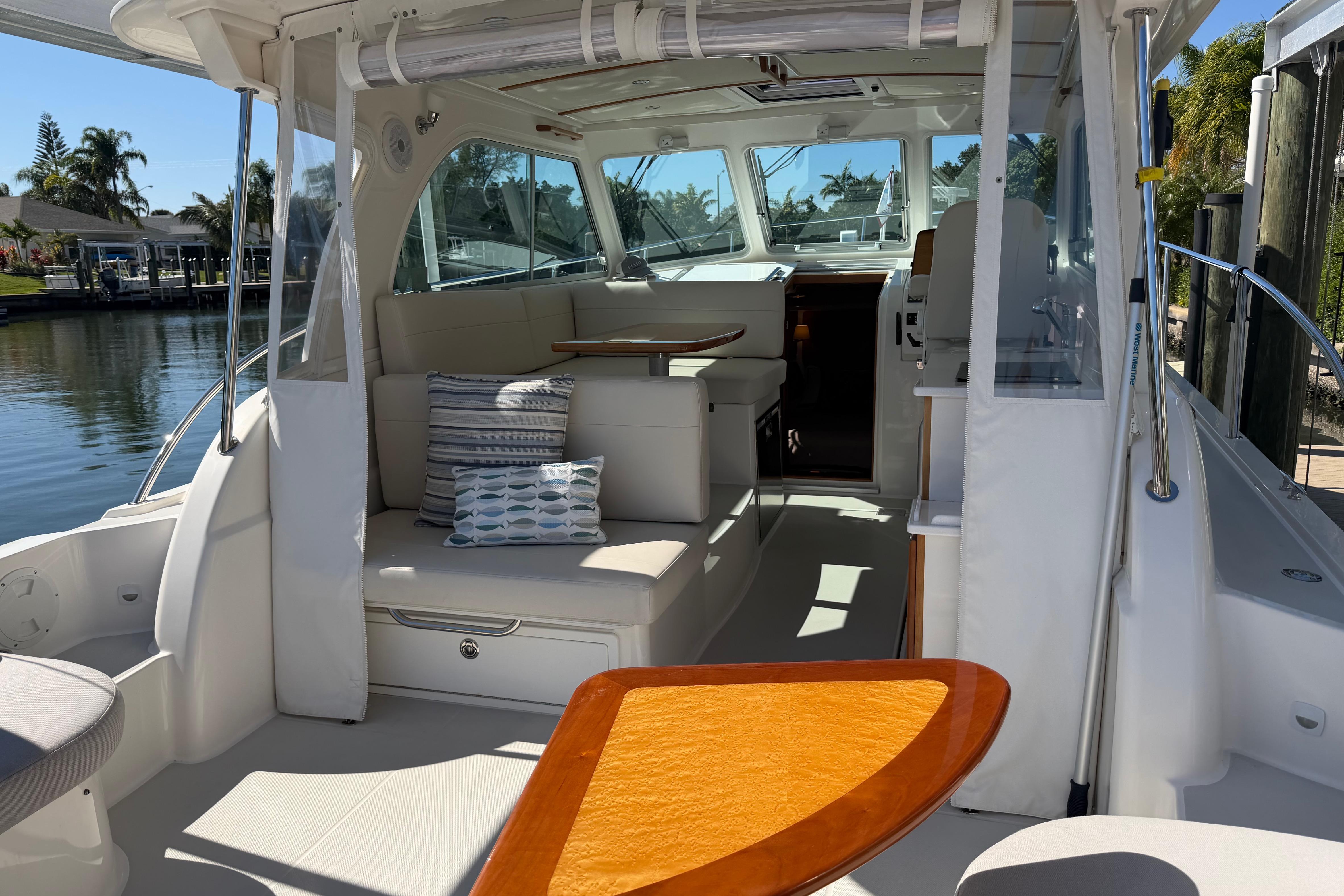 2023 Back Cove 340 boat interior with seating, table, and cushions by the water.