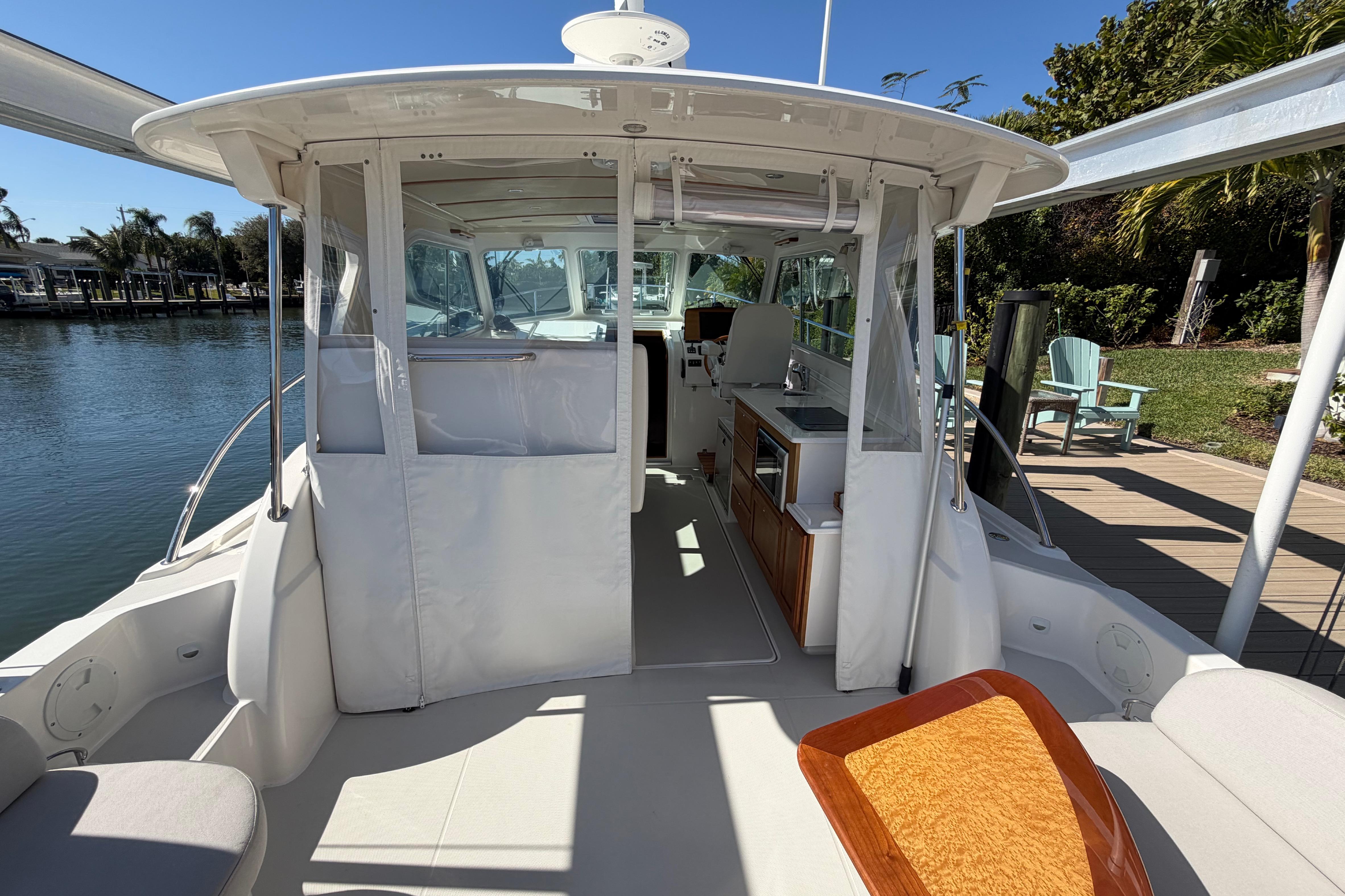 2023 Back Cove 340 boat interior with seating and kitchen area, docked by water.