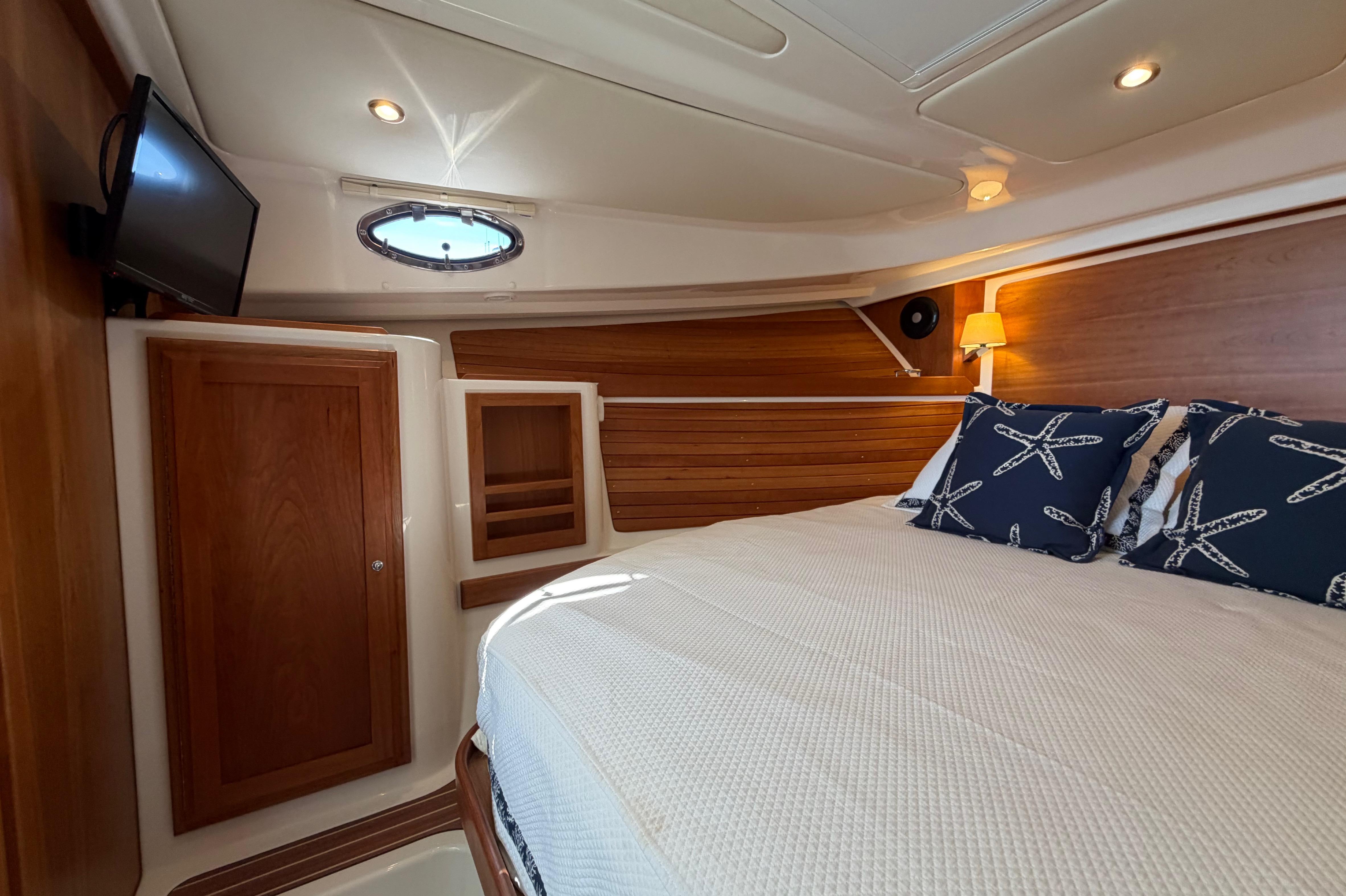 Luxurious cabin interior of 2023 Back Cove 340 boat with cozy bedding and elegant wood finish.