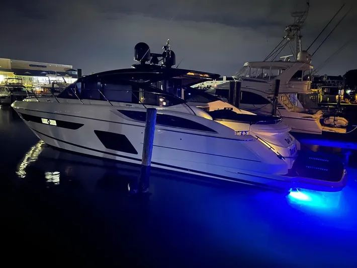 Seven Yacht Photos Pics 2018 Princess V58 yacht docked at night with blue underwater lights.