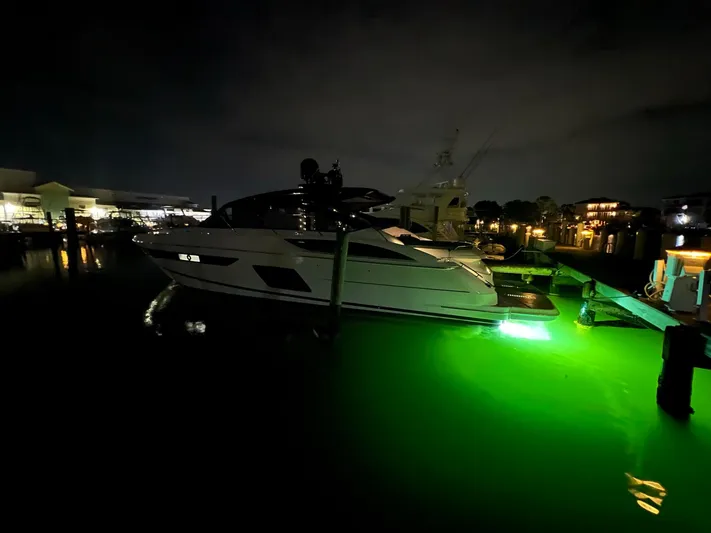 Seven Yacht Photos Pics 2018 Princess V58 yacht docked at night with glowing green underwater lights.