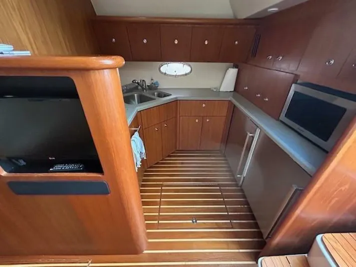 Absolutely Yacht Photos Pics 2006 Tiara Yachts Open kitchen with wood cabinetry, stainless appliances, and striped flooring.