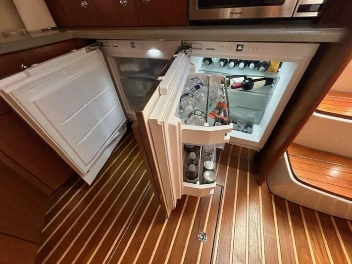 Absolutely Yacht Photos Pics Luxury yacht kitchen with open fridge, showcasing beverages and wooden flooring. Tiara Yachts Open 2006.