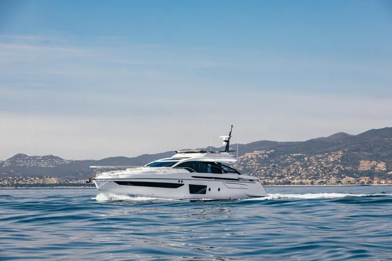  Yacht Photos Pics 2023 Azimut S8 yacht cruising on calm waters with scenic mountain backdrop.