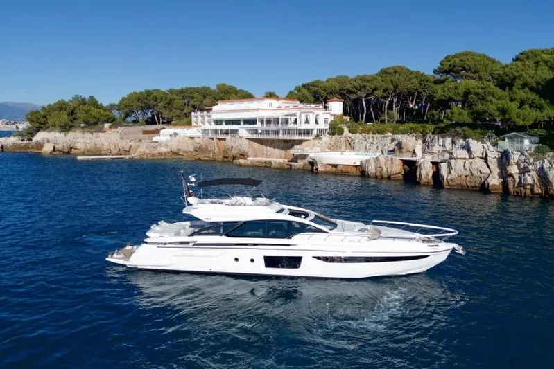  Yacht Photos Pics 2023 Azimut S8 yacht cruising near a rocky coastline with a luxury villa.