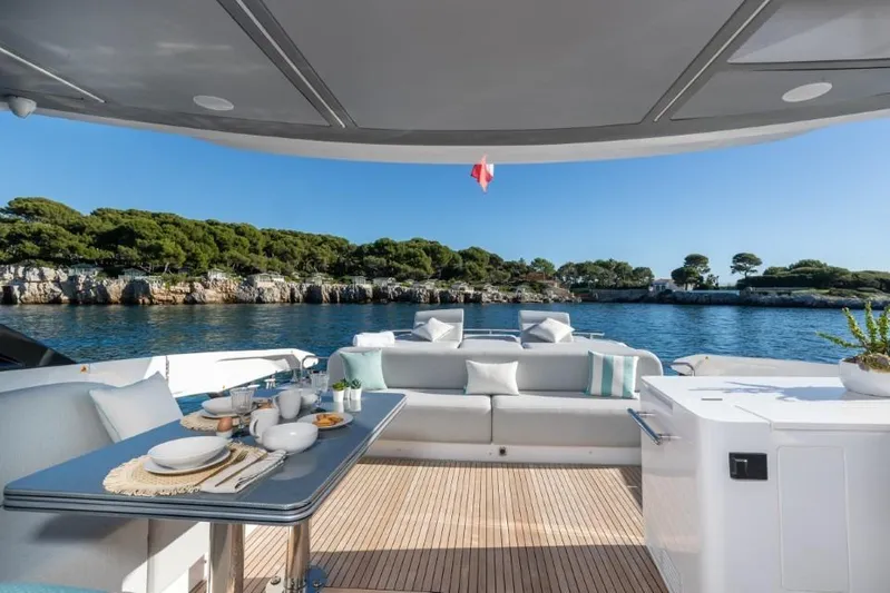  Yacht Photos Pics Luxurious 2023 Azimut S8 yacht deck with dining area, overlooking serene coastal scenery.