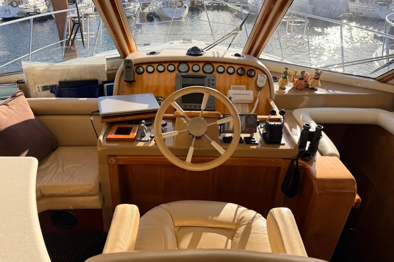 Hukilau Yacht Photos Pics Helm of 2003 Navigator 4800 yacht with steering wheel, controls, and nautical decor.