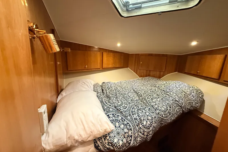 Hukilau Yacht Photos Pics Cozy cabin bedroom in 2003 Navigator 4800 yacht with patterned bedding and wooden storage cabinets.