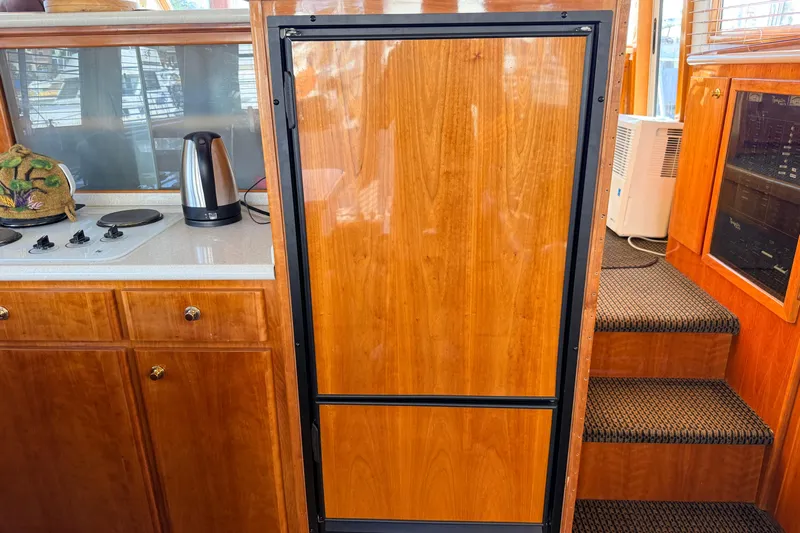 Hukilau Yacht Photos Pics 2003 Navigator 4800 yacht kitchen with wooden cabinetry, stove, and kettle.