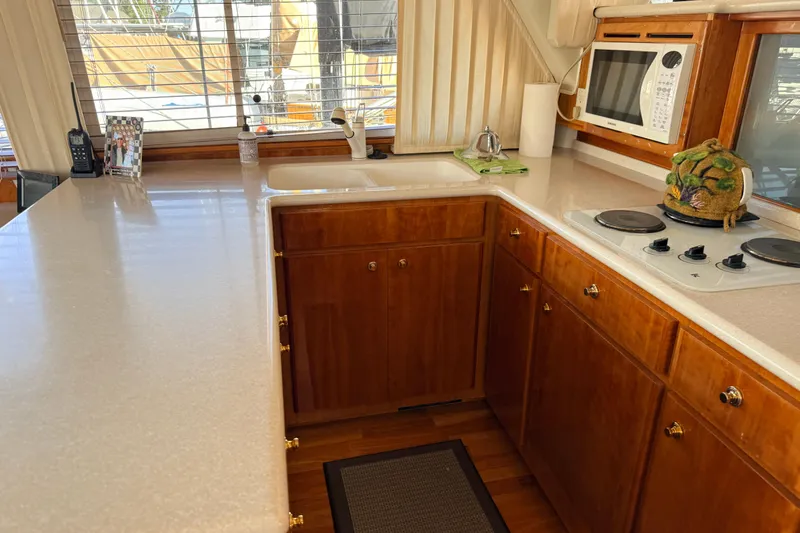 Hukilau Yacht Photos Pics 2003 Navigator 4800 yacht kitchen with wooden cabinets, stove, and microwave.