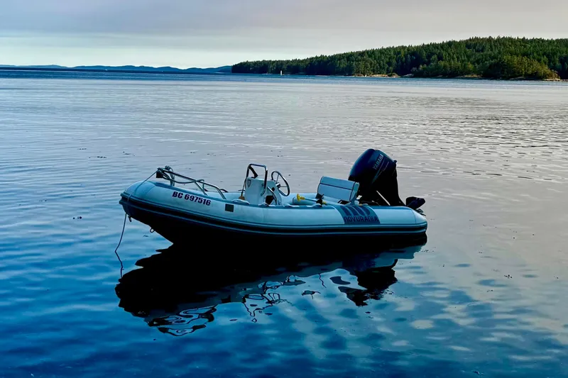 Hukilau Yacht Photos Pics Inflatable boat Navigator 4800 (2003) on calm water with forested shoreline.