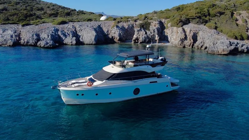 Anahita Yacht Photos Pics 2015 Beneteau Monte Carlo 6 yacht cruising in clear blue waters near rocky coastline.