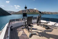 Luxury yacht Navetta 30 with gym equipment on deck, scenic mountain and sea view.