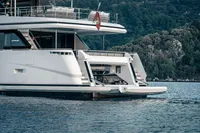 Custom Line Navetta 30 yacht, 2023 model, anchored near a forested shoreline.