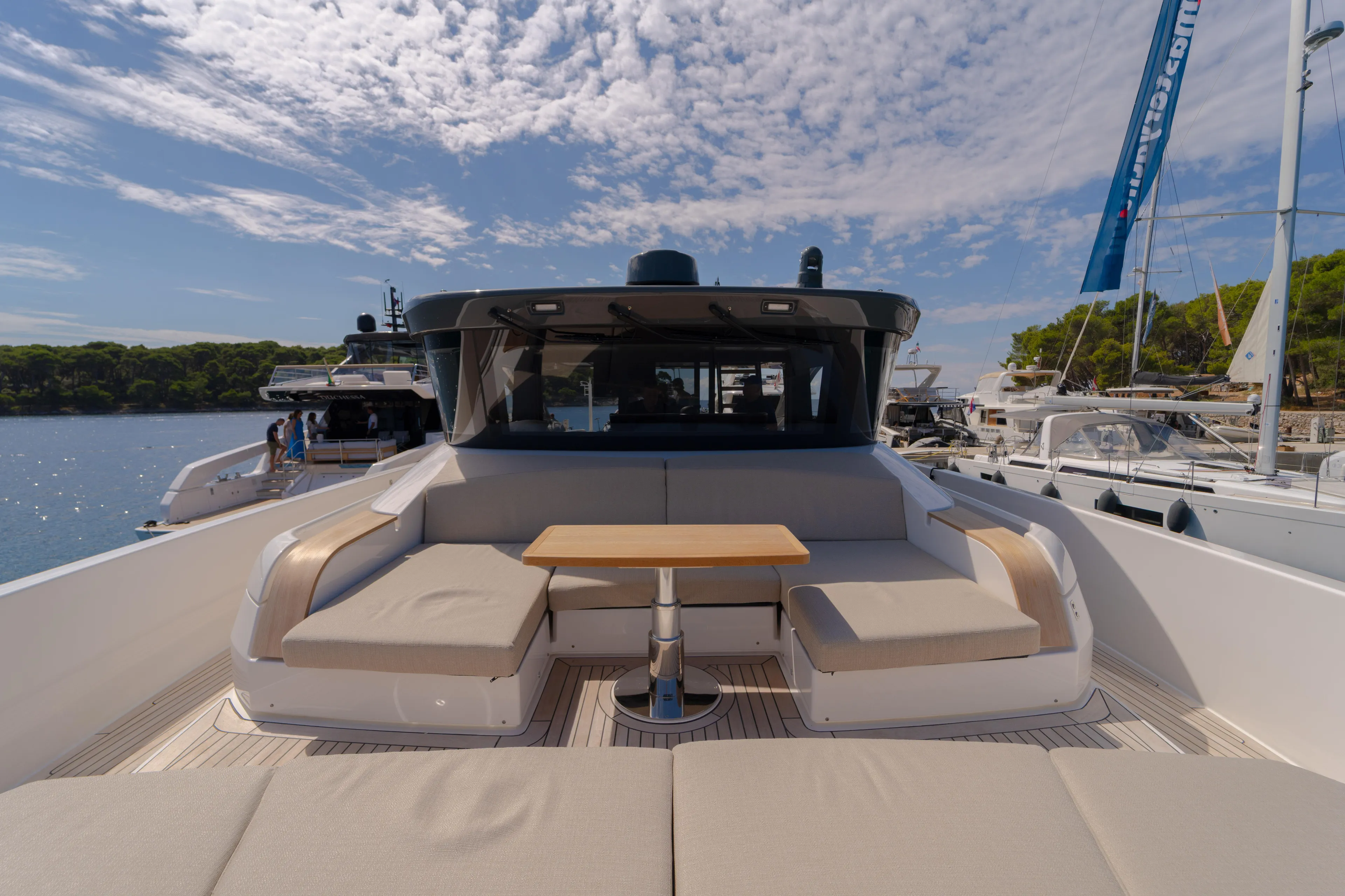  Yacht Photos Pics 2025 Bluegame BG74 yacht with spacious deck and seating, docked under a partly cloudy sky.
