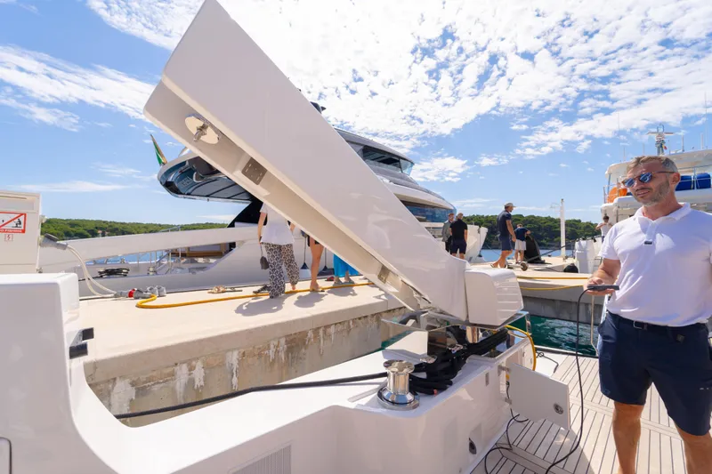  Yacht Photos Pics 2025 Bluegame BG74 yacht docked, people interacting on deck under a sunny sky.