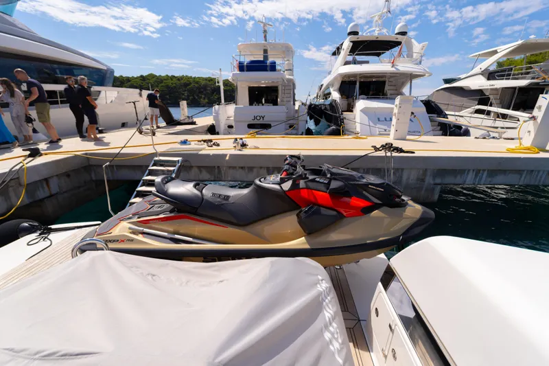  Yacht Photos Pics Docked luxury yachts and jet ski near Bluegame BG74, 2025 model, under a clear sky.